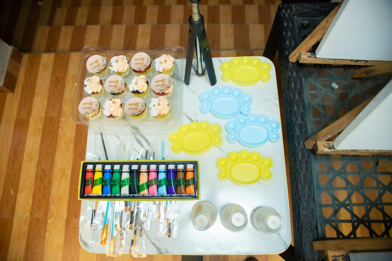 Gedeckter Geburtstagstisch von oben mit Farben, Pinseln und Cupcakes